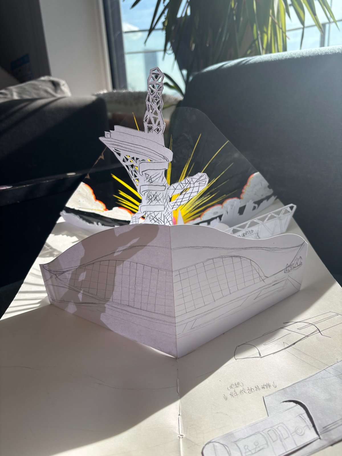 Here is East Bank — an open paper pop-up with cut-out buildings and pencil drawings of a stadium
