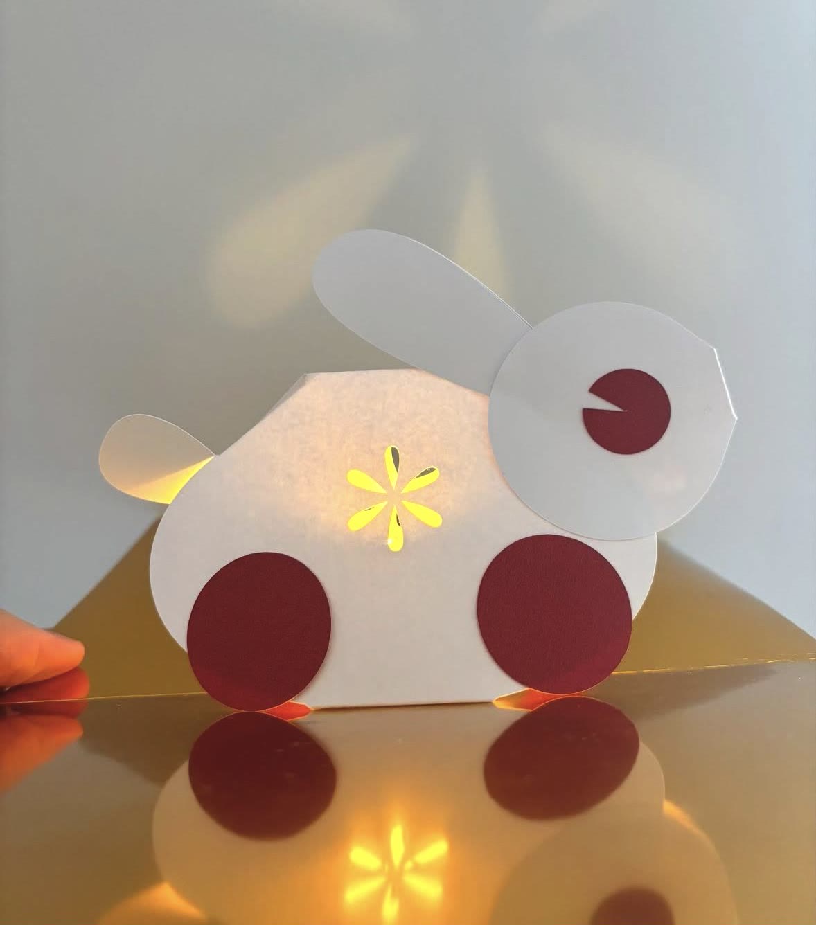 The paper rabbit pop-up card from the side, glowing yellow through a star-shaped cut