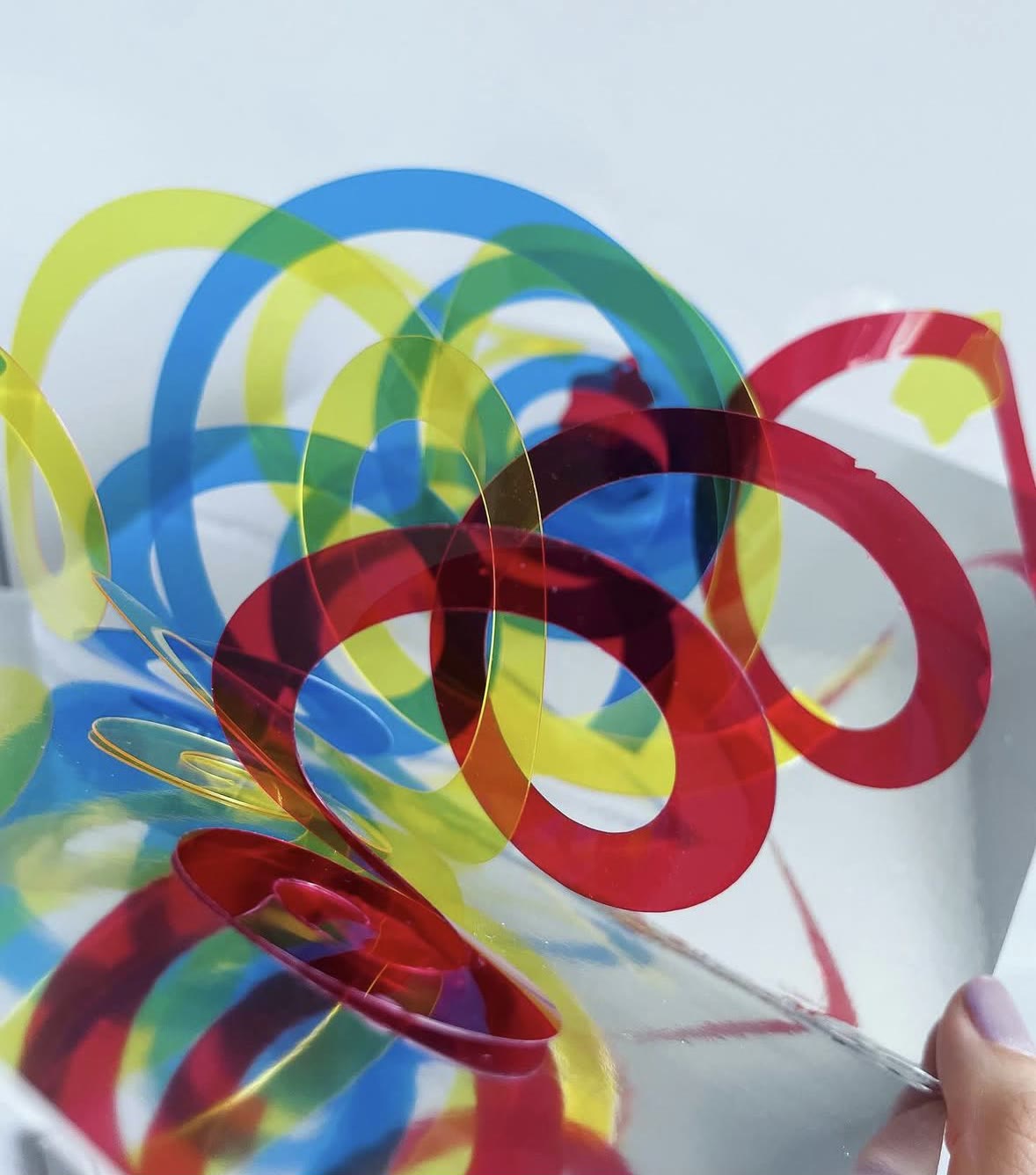 A moving pop-up mechanism made of coloured plastic strips curling out of a card