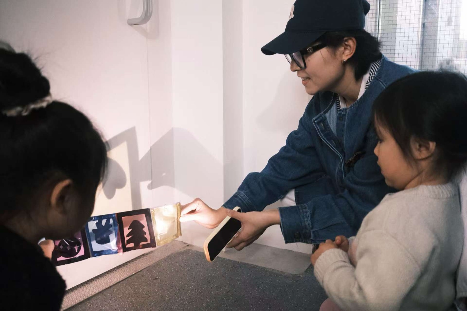 A workshop: the artist showing a light-up paper strip to two children